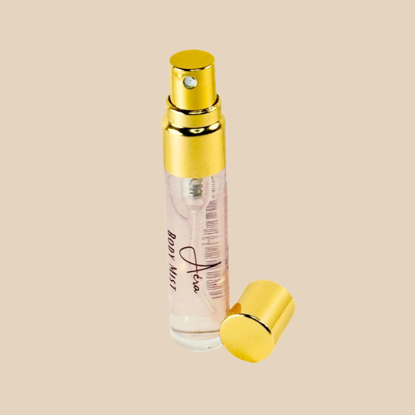 Perfume bottle with gold cap and clear body mist on a white background