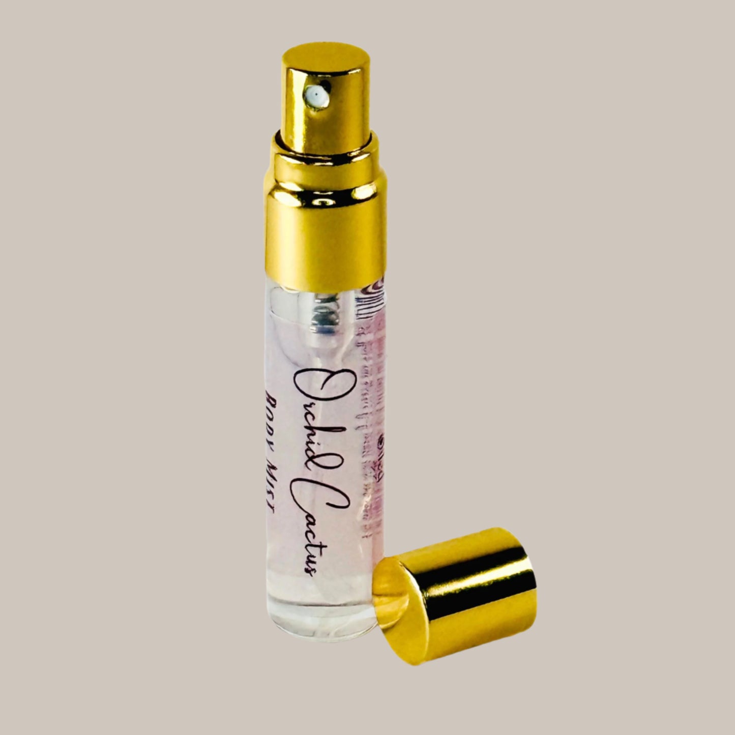 Small spray bottle with gold cap and clear body on a white background