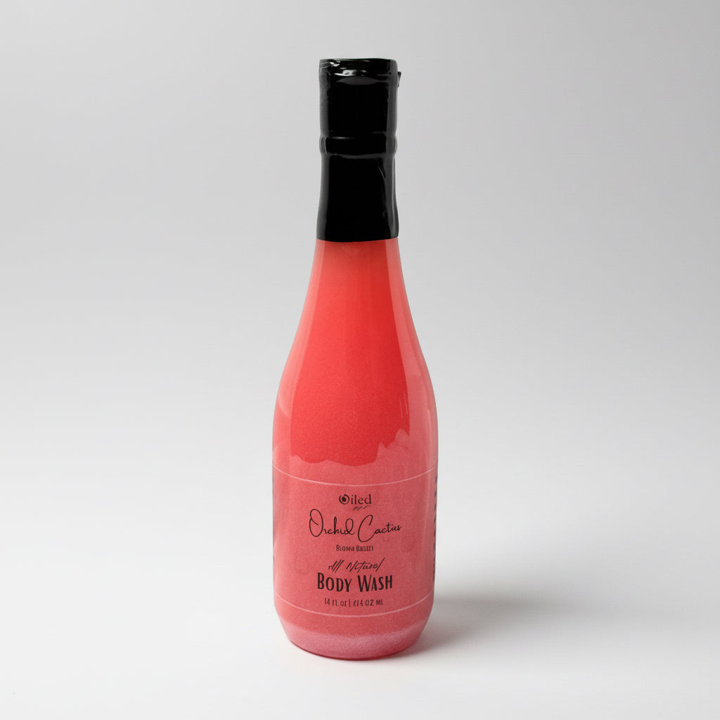 Clear bottle of pink body wash with black cap on a white background