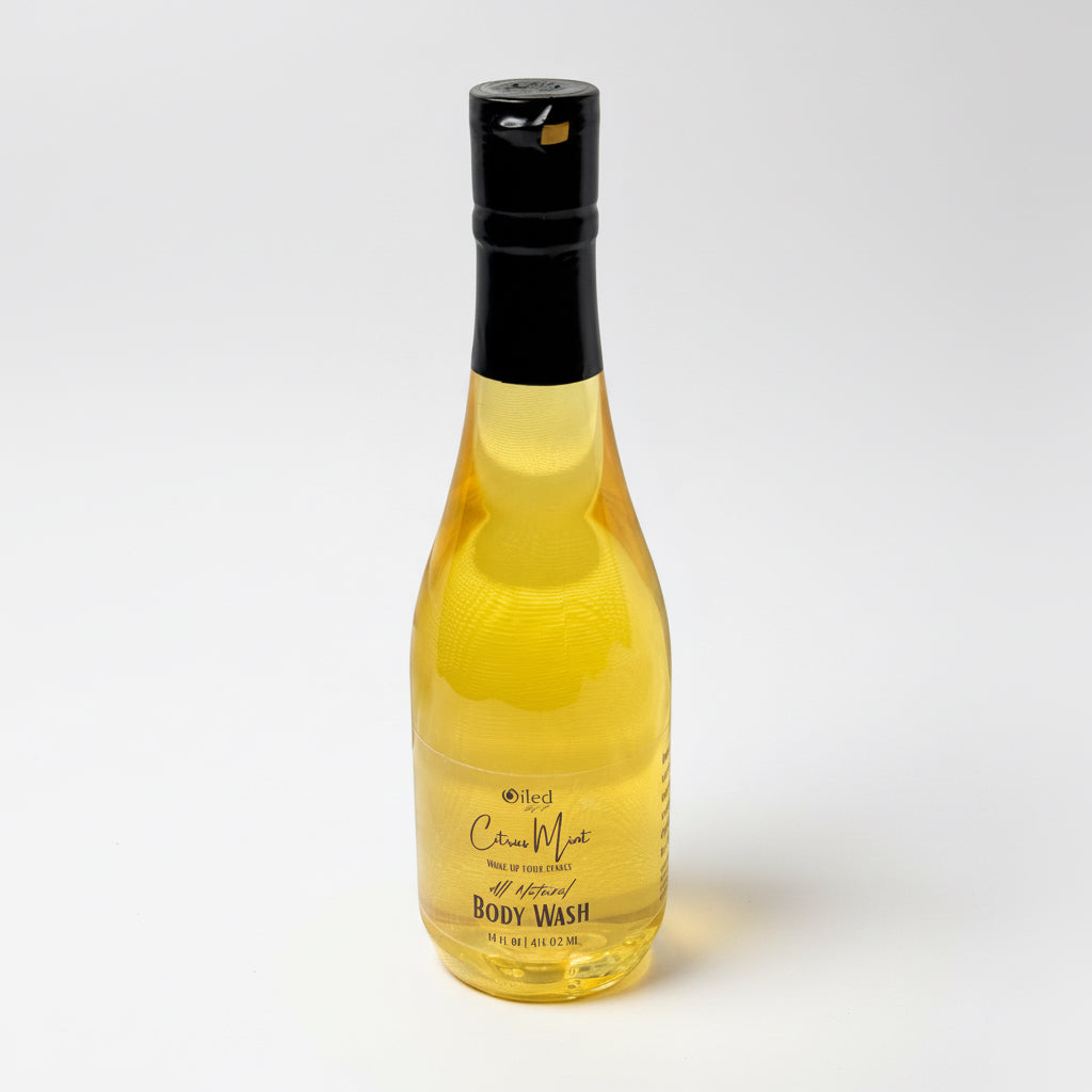 Clear bottle of yellow body wash with a black cap on a white background