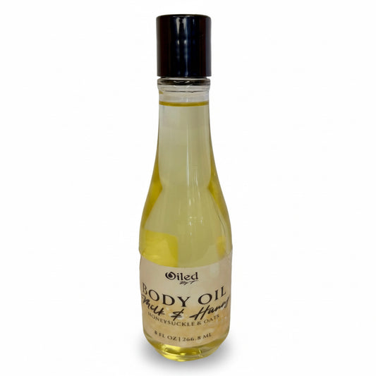 Bottle of body oil with a black cap on a white background