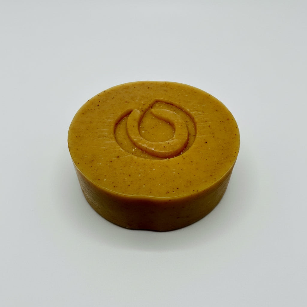 Orange bar of soap with a logo on a white fabric background