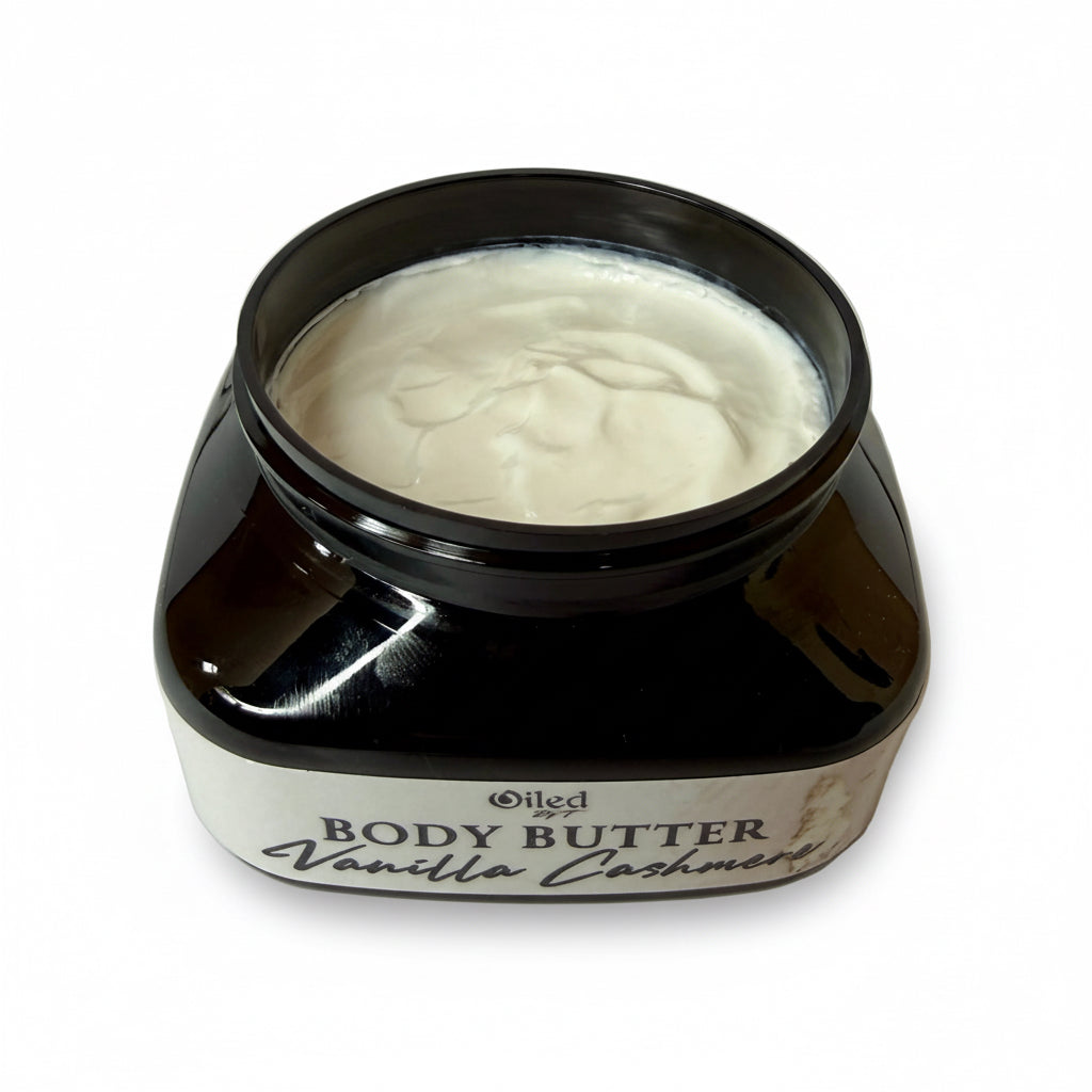 Opened black jar of body butter labeled 'Vanilla Cashmere' on a white background